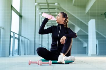 a photo of a woman drinking electrolytes while exercising 